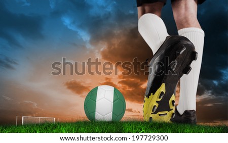 Composite image of football boot kicking nigeria ball against green grass under blue and orange sky