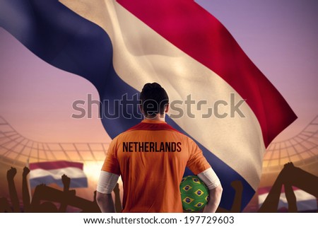 Netherlands football player holding ball against large football stadium under purple sky