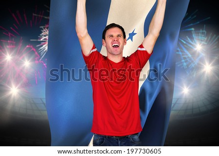 Cheering football fan in red against fireworks exploding over football stadium and honduras flag