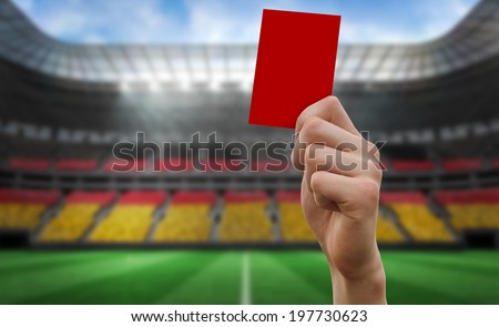 Hand holding up red card against stadium full of germany football fans
