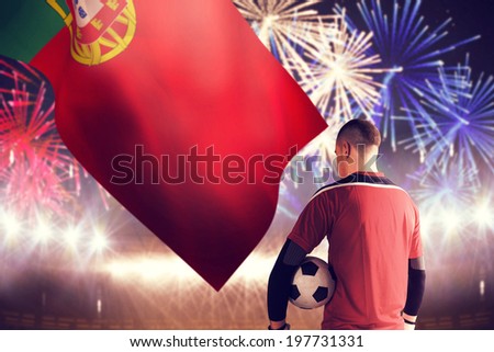 Goalkeeper in red holding the ball against fireworks exploding over football stadium