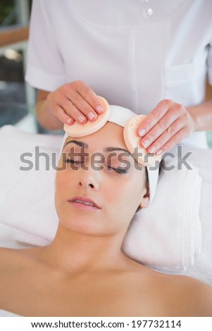 Peaceful brunette getting facial from beauty therapist in the health spa