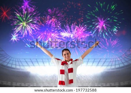 Excited asian football fan cheering against fireworks exploding over football stadium