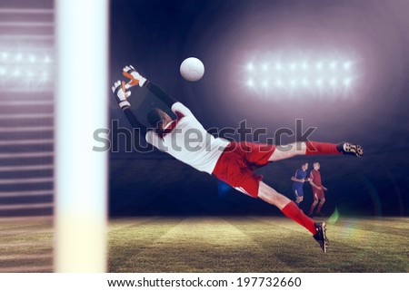 Fit goal keeper jumping up against football pitch under spotlights