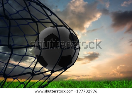 Composite image of football in back of the net under blue and orange sky
