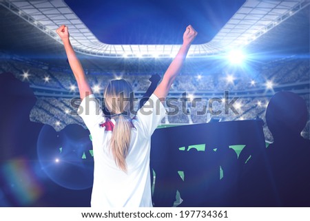 Cheering football fan in white against large football stadium with lights