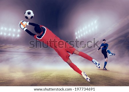 Goalkeeper in red making a save against football stadium