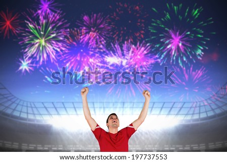 Excited football player cheering against fireworks exploding over football stadium