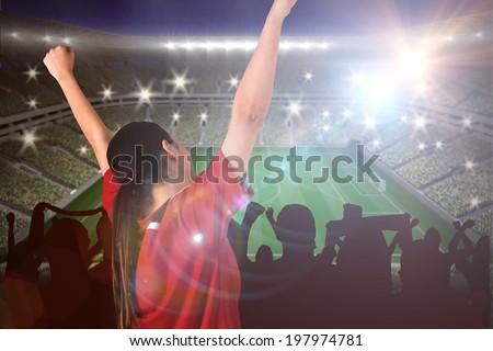Excited asian football fan cheering against large football stadium with lights