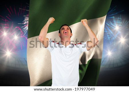 Cheering football fan in white against fireworks exploding over football stadium and nigeria flag