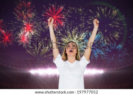 Cheering football fan in white against fireworks exploding over football stadium