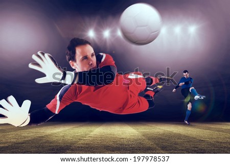 Fit goal keeper jumping up against football pitch under spotlights