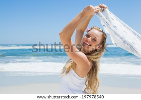 Pretty carefree blonde posing on the beach with scarf on a sunny day