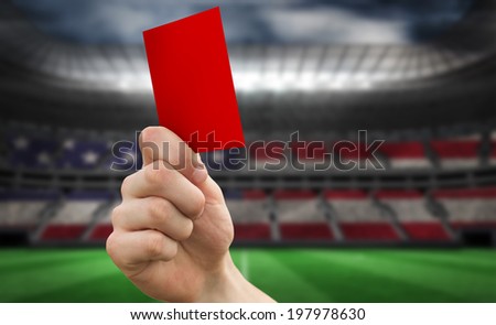 Hand holding up red card against stadium full of usa football fans