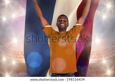 Cheering dutch football fan in orange jersey against large football stadium under bright blue sky