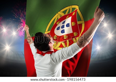 Excited football fan cheering against fireworks exploding over football stadium and portugal flag