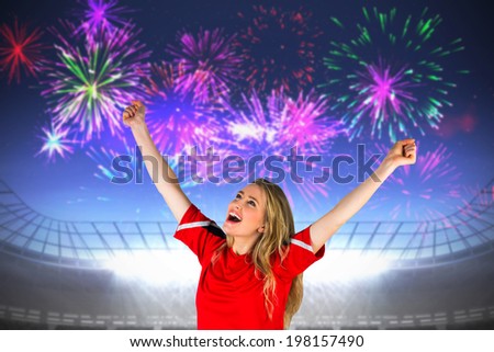 Cheering football fan in red against fireworks exploding over football stadium