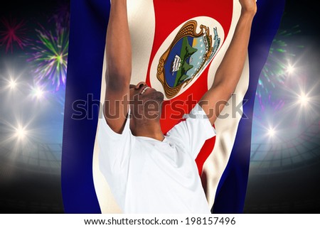 Excited handsome football fan cheering against fireworks exploding over football stadium and costa rica flag
