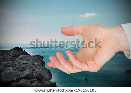 Hand presenting against large rock overlooking harbour with bridge