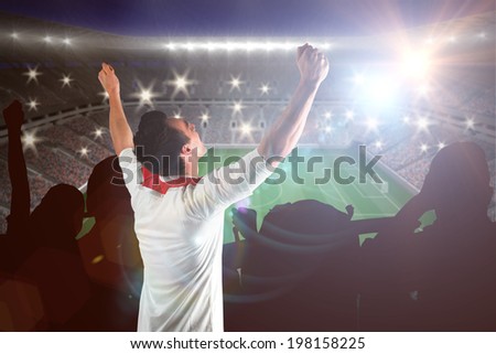 Excited football fan cheering against large football stadium with lights