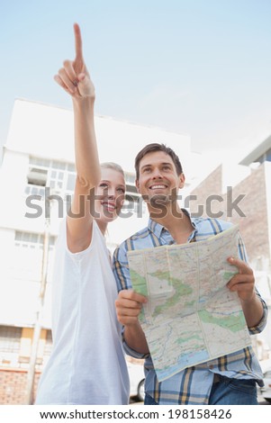 Young tourist couple looking at map and pointing on a sunny day in the city