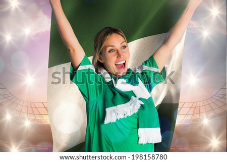 Cheering football fan in green jersey holding nigeria flag against large football stadium under bright blue sky