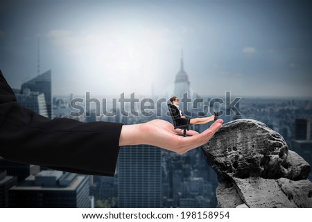 Businesswoman sitting on swivel chair with feet up in large hand against large rock overlooking dark city