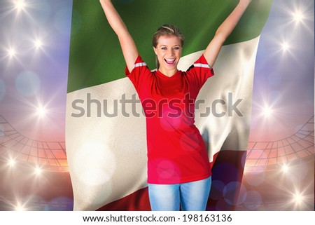 Cheering football fan in red holding italy flag against large football stadium under purple sky