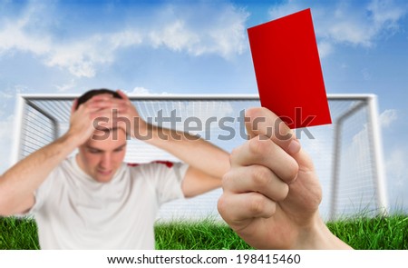 Composite image of hand holding up red card to player against goalpost on grass under blue sky