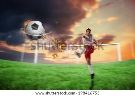 Football player in white kicking against football pitch under cloudy orange sky