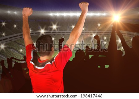 Excited football player cheering against large football stadium with lights