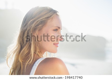 Pretty blonde standing at the beach in white sundress on a sunny day
