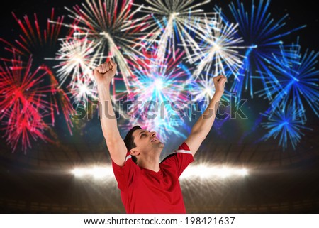 Excited football player cheering against fireworks exploding over football stadium