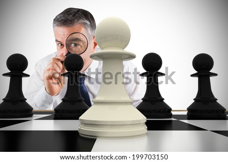 Composite image of focused businessman with magnifying glass with chessboard