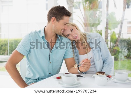 Hip young couple having desert and coffee together on the cafe terrace on sunny day