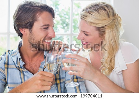 Cute smiling couple enjoying white wine together at home in the dining room