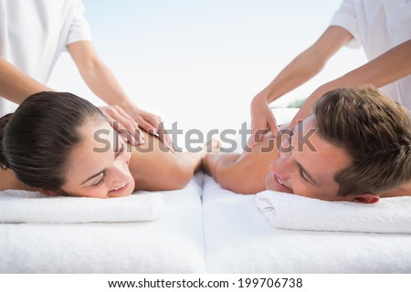 Peaceful couple enjoying couples massage poolside outside at the spa