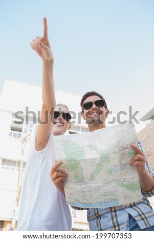 Young tourist couple looking at map and pointing on a sunny day in the city