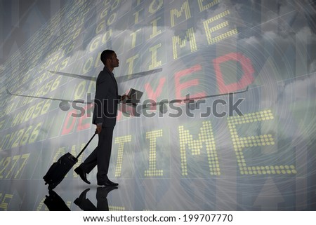 Young businessman pulling his suitcase against airport departures board