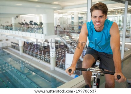 Smiling fit man on the spin bike at the gym