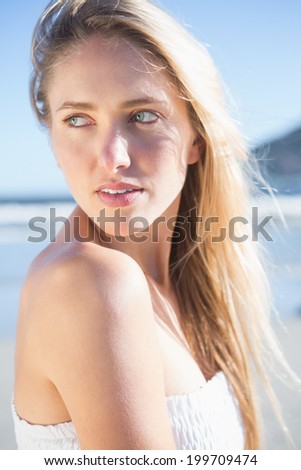 Woman in white dress posing on the beach on a bright day