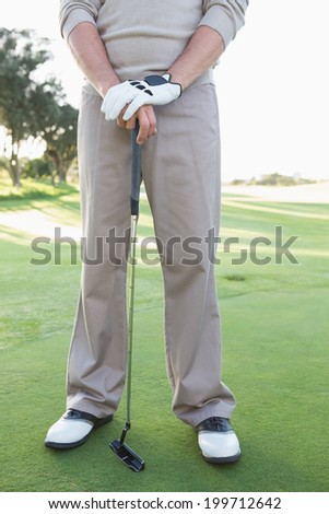Low section of golfer standing with club on a sunny day at the golf course