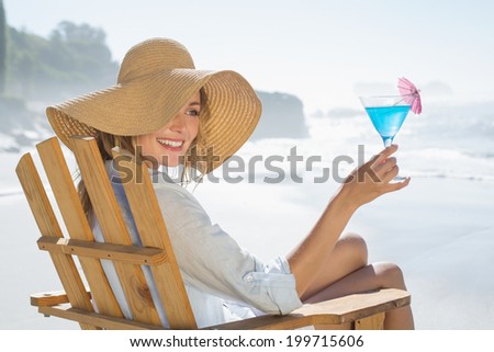 Woman relaxing in deck chair by the sea holding cocktail on a sunny day