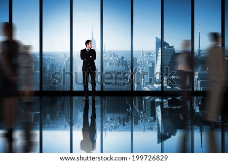 Businessman with arms crossed against room with large window looking on city