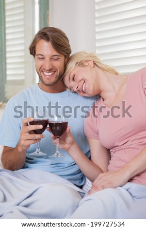 Happy couple sitting on couch with red wine at home in the living room