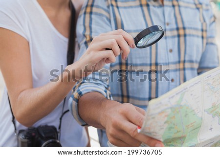 Young tourist couple using magnifying glass on the map on a sunny day in the city