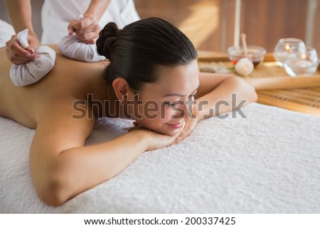 Content brunette enjoying a herbal compress massage at the health spa