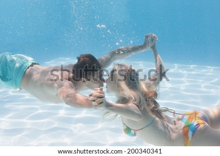 Cute couple kissing underwater in the swimming pool on their holidays
