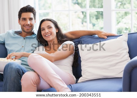 Attractive couple watching tv on the couch at home in living room