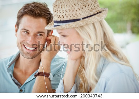 Cute couple listening to music together in cafe on a sunny day in the city